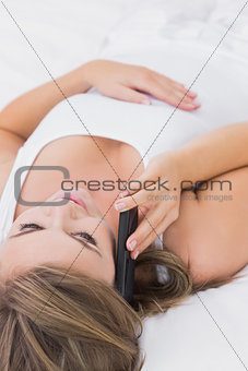Blonde woman phoning lying on the bed