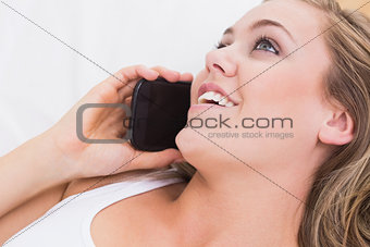 Blonde woman phoning in the bedroom