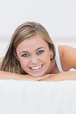 Smiling blond woman lying on her bed