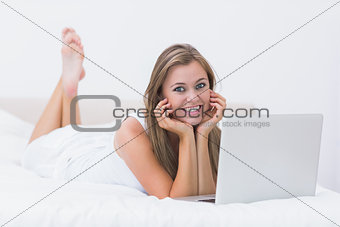 Woman lying on the bed with her laptop