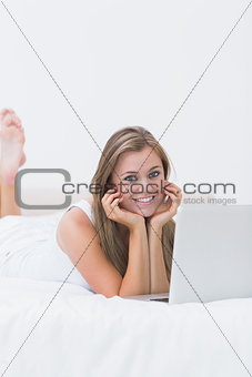 Blonde woman lying on the bed with her laptop