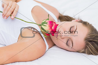 Blonde woman lying on the bed with a rose