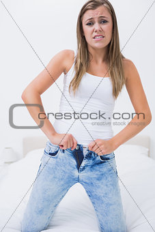 Discouraged woman trying to close her jeans