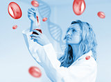 Woman in labcoat looking at beaker of blood