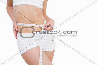 Fit woman measuring waist with measuring tape