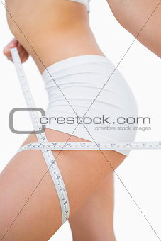 Woman measuring thigh with measuring tape