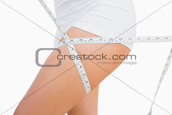 Midsection of fit woman measuring thigh