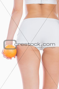 Midsection of fit woman with orange