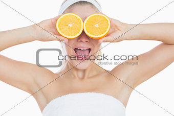 Surprised woman holding orange slices in front of eyes