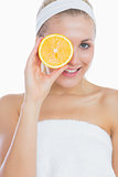 Happy woman holding orange slice in front of eye