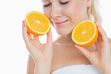 Woman with eyes closed holding slices of orange