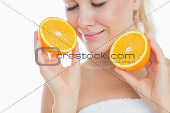 Woman with eyes closed holding slices of orange