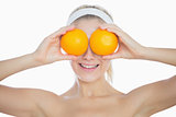 Happy woman holding oranges in front of eyes