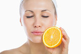 Woman with eyes closed holding orange slice