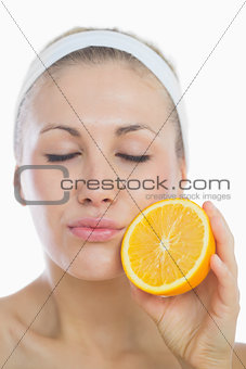 Young woman with eyes closed holding orange slice