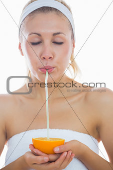 Woman sipping from an orange with straw