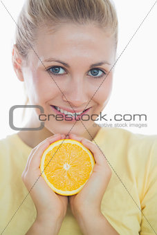 Happy woman showing slice of orange
