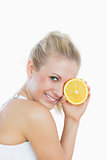 Woman holding slice of orange in front of eye