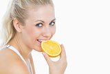 Happy woman biting slice of orange