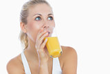 Woman drinking orange juice as she looks up