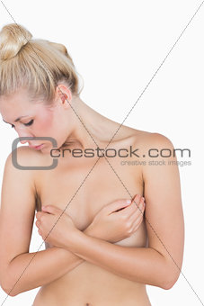 Naked woman covering her breasts with hands