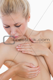 Naked woman examining her breast