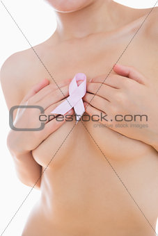 Woman holding breast cancer ribbon over breasts