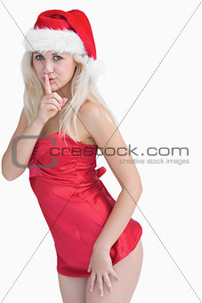 Young woman wearing santa hat with finger on lips