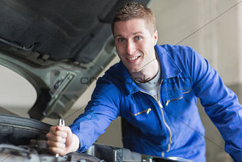 Male mechanic working on automobile engine