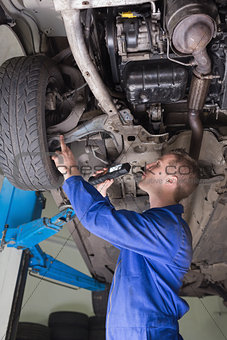 Auto mechanic examining under car