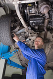 Male mechanic examining under vehicle