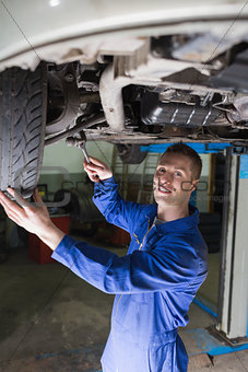 Confident mechanic repairing car