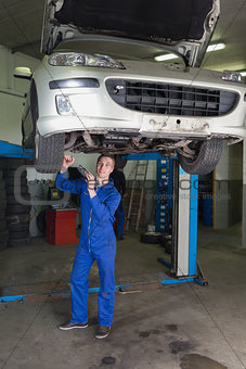 Mechanic working under raised car in workshop
