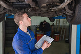 Mechanic under car preparing checklist
