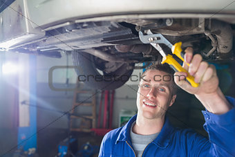 Happy mechanic repairing car with pliers