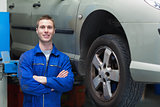 Confident male mechanic standing by car