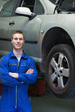 Happy mechanic standing by car