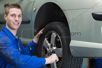 Happy mechanic changing car tyre