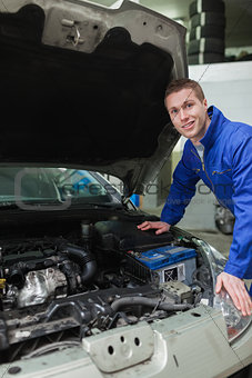 Happy mechanic repairing car engine