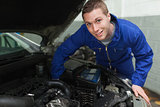 Happy mechanic repairing under car hood