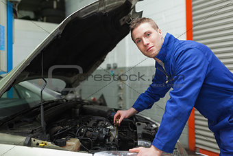 Confident mechanic checking car engine oil