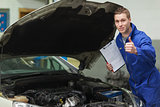 Mechanic with clipboard gesturing thumbs up