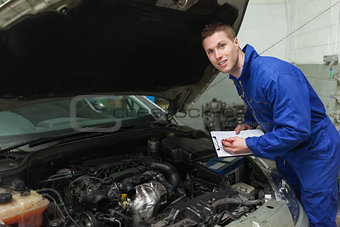 Mechanic with clipboard by car