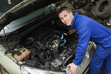 Happy mechanic examining car engine