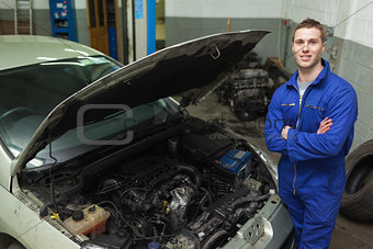 Confident repairman by car with open hood