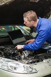 Repairman with laptop checking car engine