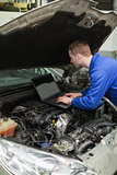 Mechanic using laptop on car engine