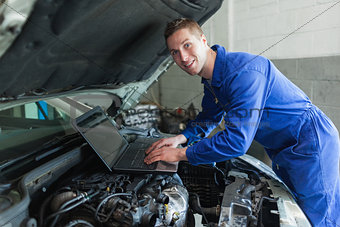 Male auto mechanic using laptop