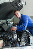Mechanic using laptop on car engine