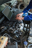 Mechanic hands using laptop on car engine
